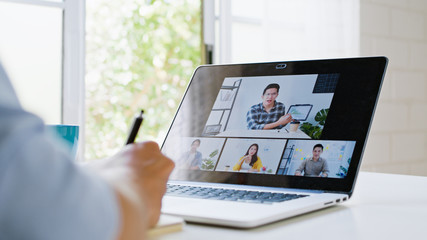 Asian man video call conference, online remote meeting with business coworker, at home. New normal lifestyle, social distancing, internet technology, businessman work from home concept