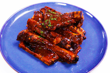 smokey barbeque sauce glazed baby pork ribs in a plate with white background