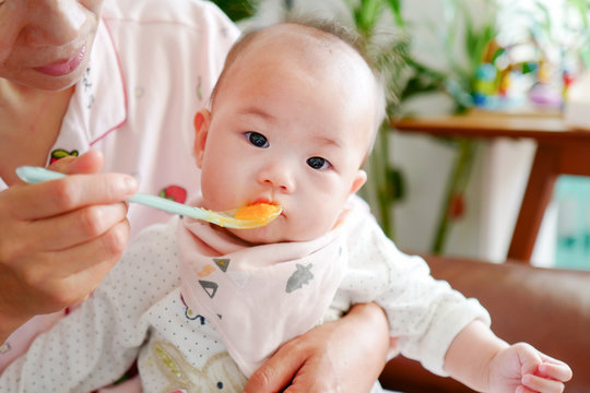 Portrait of cute little baby girl with carrot puree on the mouth