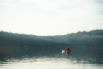 Kakya floats on the lake in the fog. Which guy is sitting in a life jacket
