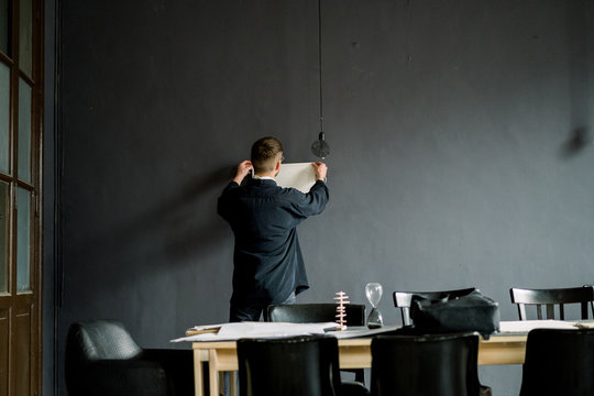 Male designer attaching drafts to wall