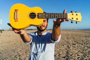 Chico joven sujetando un ukelele amarillo en la playa © MiguelAngelJunquera