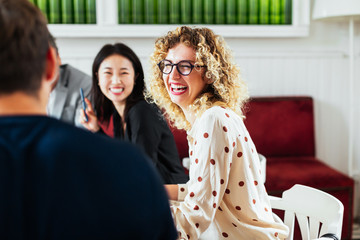 Businesswoman laughing at joke amidst colleagues