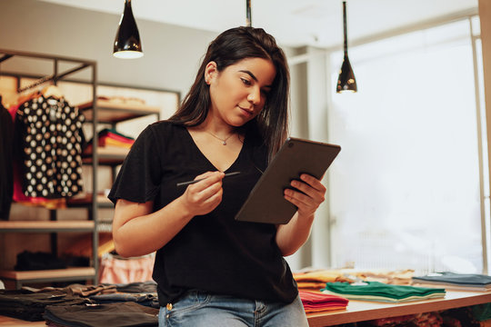 Latin Woman Owner Of Small Business. Entrepreneurial Woman Working In Her Clothing Store.