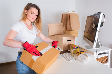 Online shop. The owner of the online store packs parcels for sending. Delivery of orders to the buyer. The businesswoman works. Preparing products for delivery.