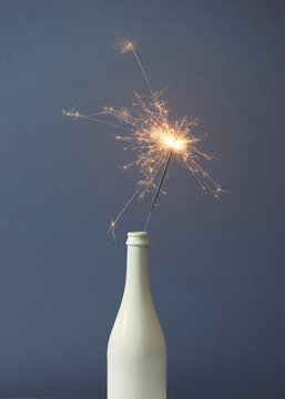 Champagne bottle with sparklers on grey background. Flat lay.