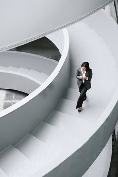Businesswoman on office staircase using smartphone