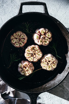 Garlic cloves with rosemary in cast iron