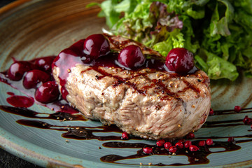 Juicy tasty beef tenderloin steak with cherry jam and green salad. Hearty meat dish