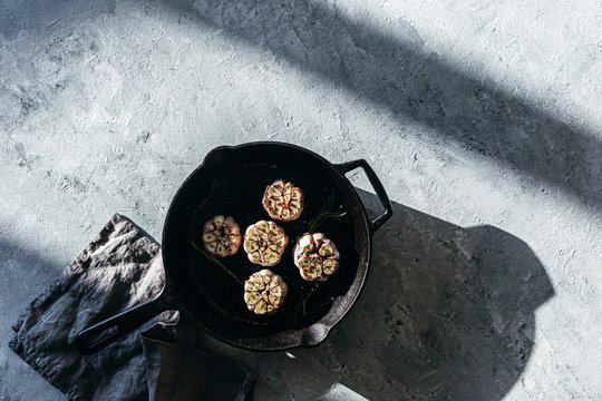 Garlic cloves with rosemary in cast iron