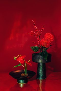Amazing mix of red flowers and red small berries on branches in black and green vases