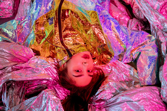 Futuristic ethnic woman lying on metallic film