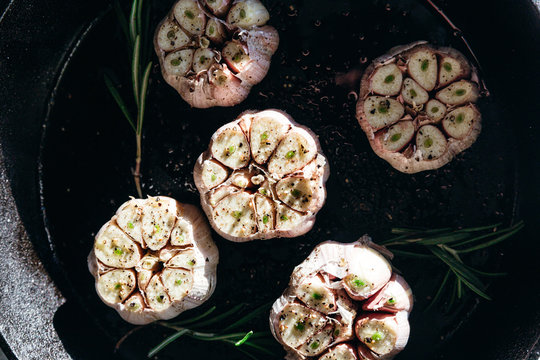 Garlic cloves with rosemary in cast iron