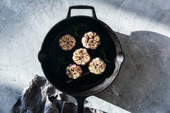 Garlic cloves with rosemary in cast iron