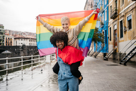 Two women carrying a LGTB flag at street