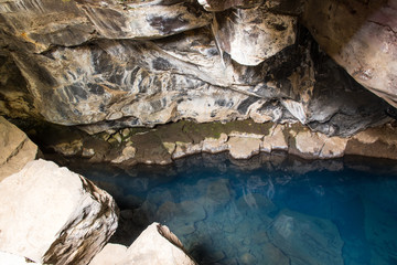 Natural Geothermal hot spring in the cave Grjotagja, Iceland blue water and colorful lava stones