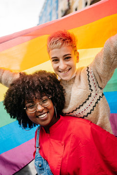 Two women carrying a LGTB flag at street