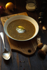 Mushroom soup-puree in a white plate on a wooden Board and a vintage spoon. Low key, close-up