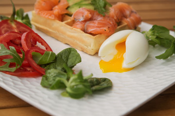 waffle with slices of salted salmon, avocado and poached egg. the concept of a healthy Breakfast