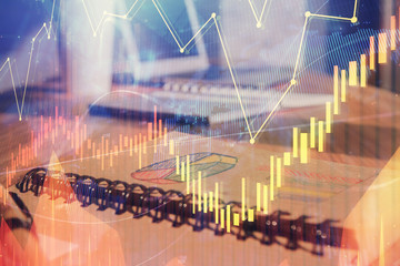 Double exposure of financial graph drawings and desk with open notebook background. Concept of forex market