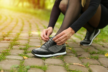 beautiful sports sneakers on women's legs. woman tying laces on sneakers