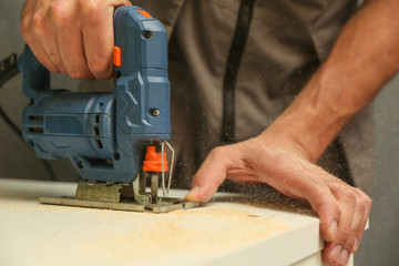 refurbishment in the apartment. carpenter's hands are sawing with electric jigsaw