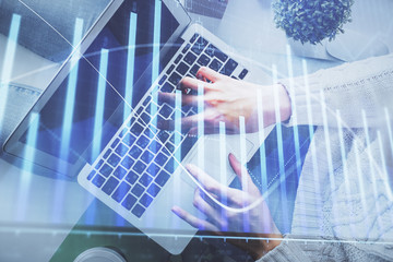 Double exposure of woman hands working on computer and forex chart hologram drawing. Top View. Financial analysis concept.