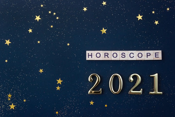 Word Horoscope and 2021 numbers. Wooden blocks with letters on blue background decorated with starry confetti. Copy space