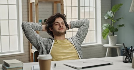 University student studying at home, completing his assignment. Young caucasian freelancer relaxing in his chair after finishing his project at home 4k footage
