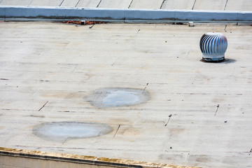 Ponding water on the settled flat roof. Turbine vent on the flat roof of an industrial building.