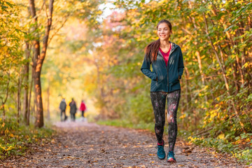 Woman walking in autumn forest nature path walk on trail woods background. Happy girl relaxing on active outdoor activity. - 372360399