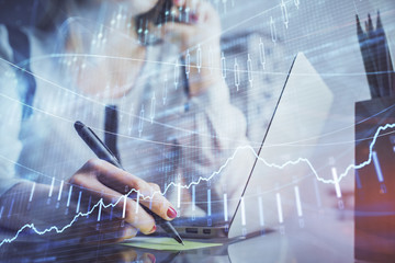 Double exposure of woman hands typing on computer and financial graph hologram drawing. Stock market analysis concept.