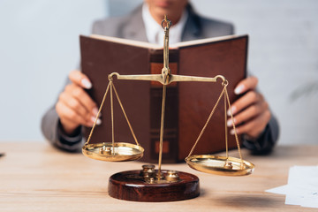 selective focus of golden scales near lawyer with book