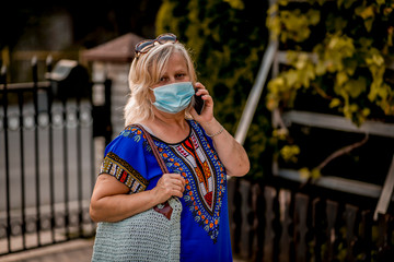 Senior woman talking on mobile phone. She wearing a protective face mask.
