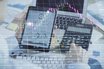 Double exposure of man's hands holding and using a digital device and forex graph drawing. Financial market concept.