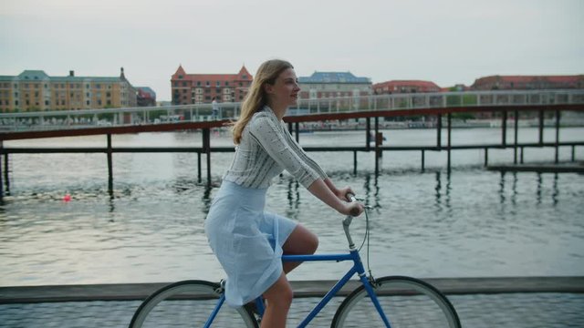 Woman Riding Bicycle Along City Waterfront