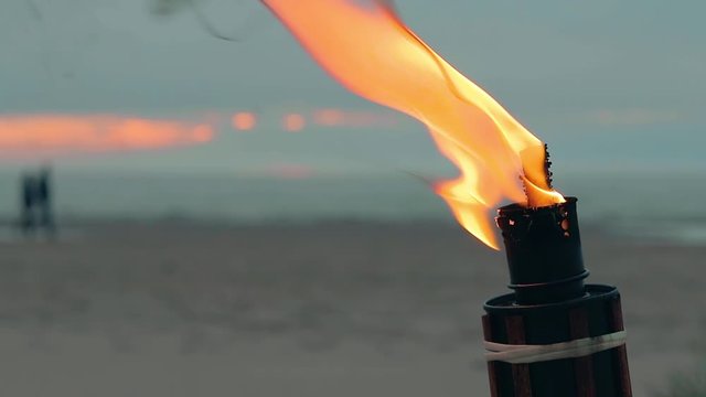 Tropical Bambo Torch Burning in the Beach at Summer Evening. Decorative Candle Has a Massive Orange Flame Using Oil Fuel or Kerosene. Closeup Static Shot
