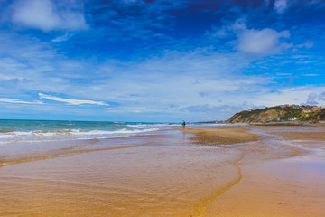 Obraz premium man walking on beach. ocean shore with blue sky and sand