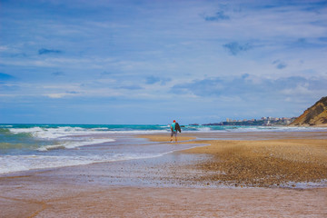 people walking on the beach. man walking on beach. ocean shore with blue sky and sand