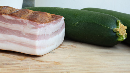 Smoked bacon meat with lots of fat on it on a wooded board ready to be carved. The meat is salt-cured and from a pig's belly or back.