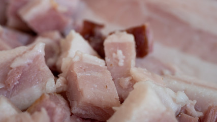 Smoked bacon meat with lots of fat on it, carved and diced on a wooded board.
The meat is salt-cured and from a pig's belly or back.