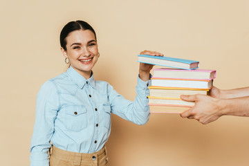 student in denim shirt taking books on beige