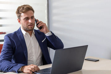 young business man at the desk in front of the computer and cell phone