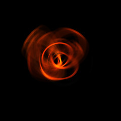 Spinning rays of light isolated on black background. Graphic 2D illustration of glowing colorful light particles in circular motion.