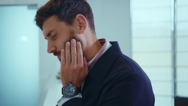 Handsome businessman in suit stand feel pain in tooth problem sadness sick stress toothache touch unwell close up slow motion