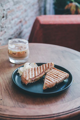 Woman eating grill sandwich ham cheese and salad ( lettuce, ham, cheese, tomato and potato chip)with a cup of coffee for Breakfast meal in morning.