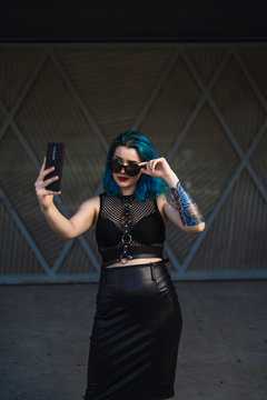 Chica alternativa con el pelo azul y tatuajes posando