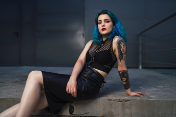 Chica alternativa con el pelo azul y tatuajes posando