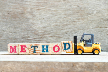 Toy forklift hold letter block d to complete word method on wood background