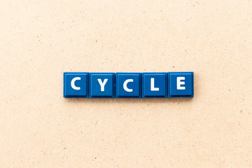 Tile letter in word cycle on wood background